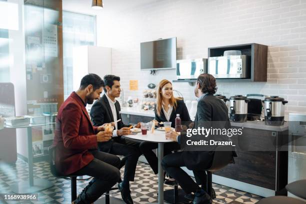 duizendjarige latijnse collega's die een pauze op het werk nemen, snacks eten en chatten. - kantine stockfoto's en -beelden