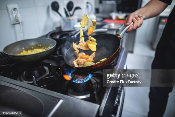 cozinheiro chefe que prepara o alimento sobre um fogão de gás flamejante - boca de fogão a gás - fotografias e filmes do acervo