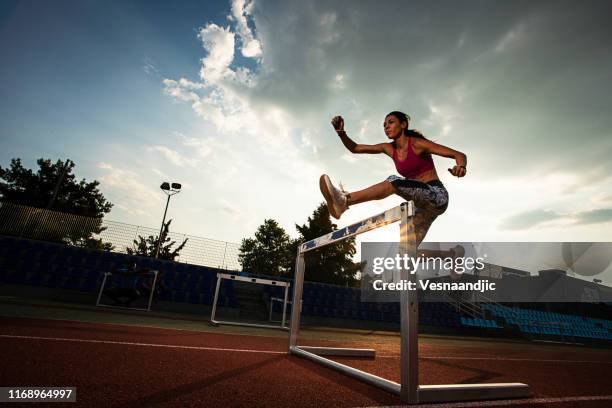 athletin frau bereitet sich vor und rennt hürden für leichtathletik - hurdles stock-fotos und bilder