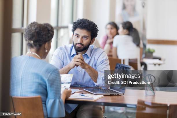 bank customer considers opening a new account - bank manager meeting stock pictures, royalty-free photos & images