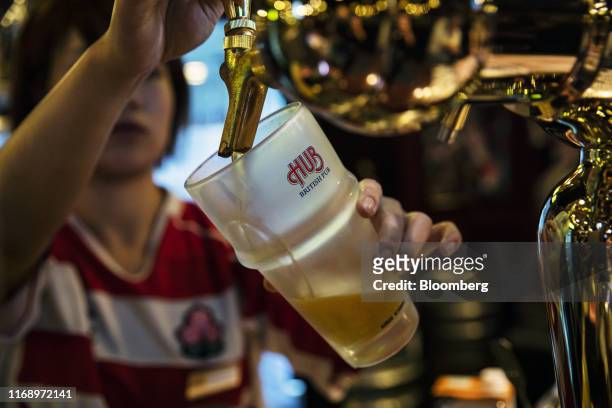 An employee pours a glass of Heineken NV beer at a Hub Co. Pub in Tokyo, Japan, on Friday, Sept. 6, 2019. Foreigners are expected to drink about four...