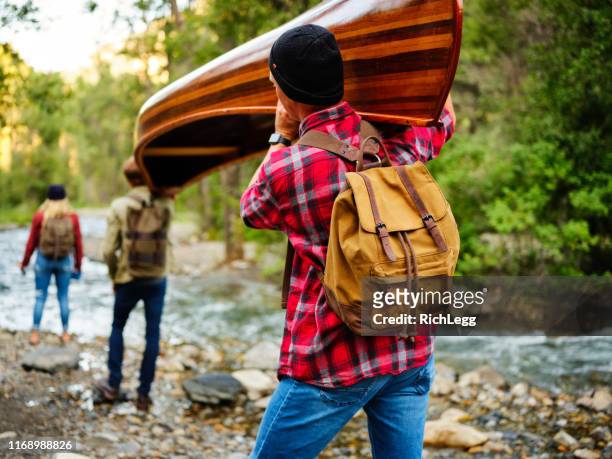 young adults with a canoe in the wilderness - carrying kayak stock pictures, royalty-free photos & images