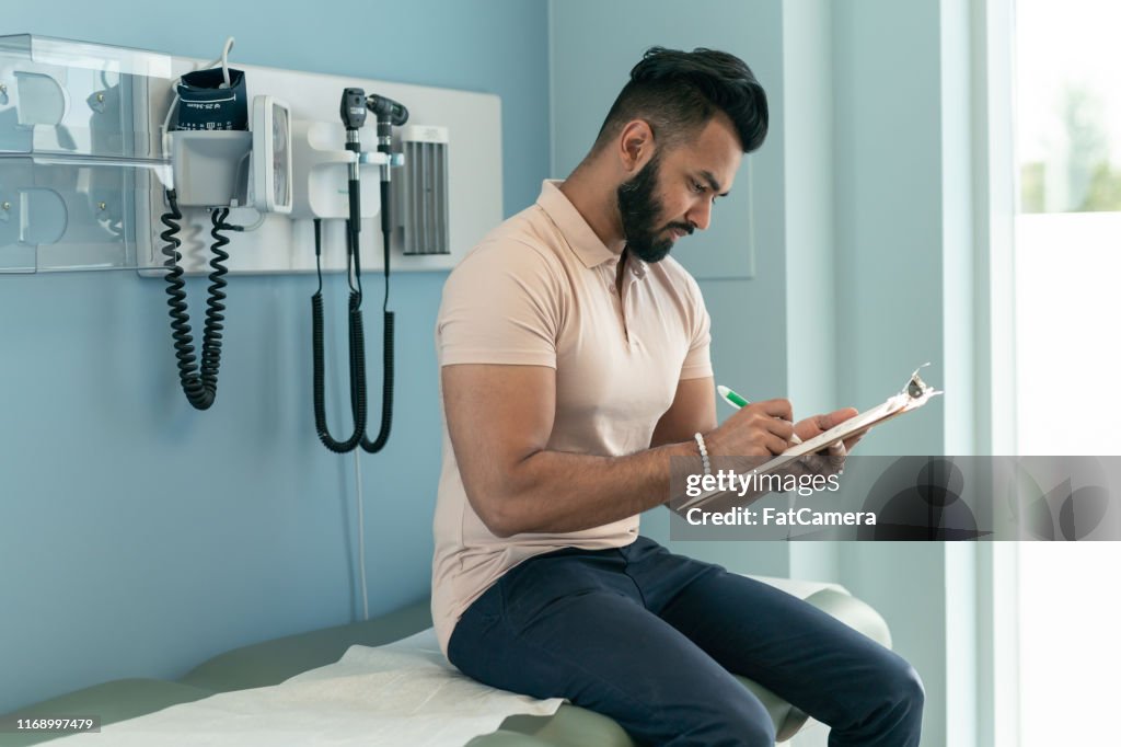 Young man filling out paperwork before medical appointment