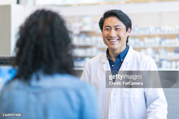 mannelijke apotheker bijstaan vrouw met recept medicatie - apotheker stockfoto's en -beelden