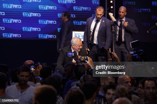 People take photographs and video footage as Benny Gantz, leader of the Blue and White party, seated center, speaks to his supporters in Tel Aviv,...