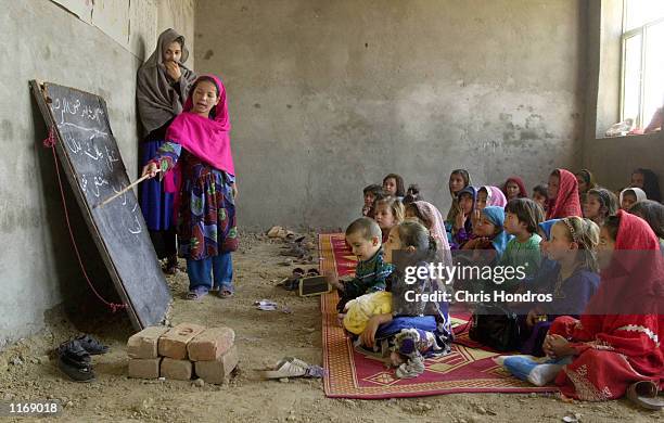 An Afghan refugee student reads Arabic script from the blackboard October 18, 2001 at the Shamshatu Afghan refugee camp in Pakistan, near the border...