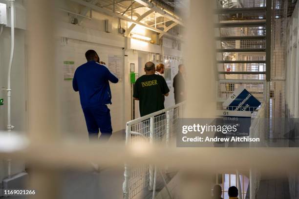 Two male prisoners walk down the landing towards to Prison Officers in G Wing Level 2 of Her Majestys Prison Pentonville, London, United Kingdom.