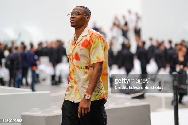 Russell Westbrook wears necklaces, a yellow and orange tie-and-dye shirt, black pants, outside Dior, during Paris Fashion Week - Menswear...
