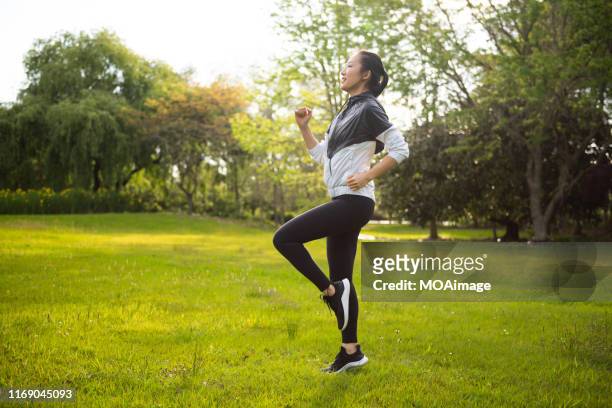 a young asian female wearing sportswear doing fitness on the outdoor lawn - auckland train bildbanksfoton och bilder