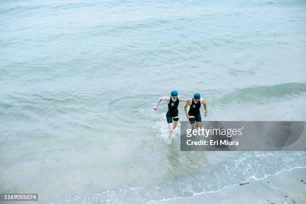 Visually impaired female triathlete with her guide coming up from the sea