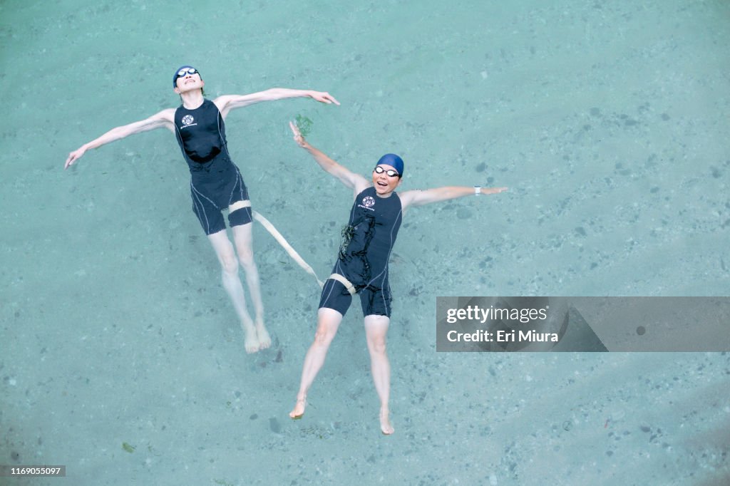 彼女のガイドと一緒に海で泳いでいる視覚障害の女性トライアスリートの真上からの眺め
