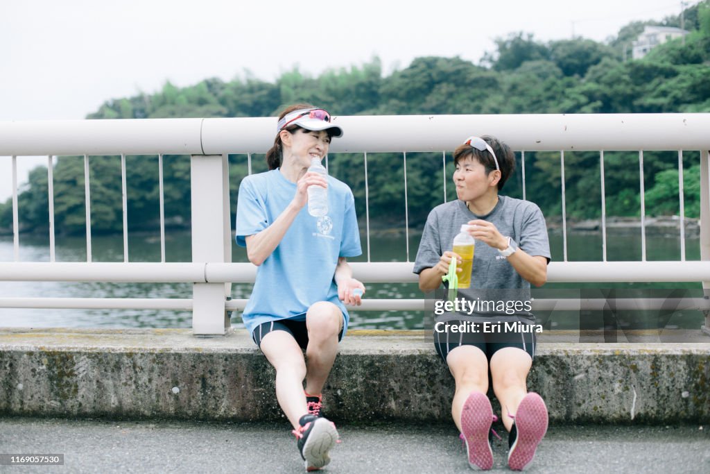 Visually impaired female triathlete taking a break from training together with her guide and coach