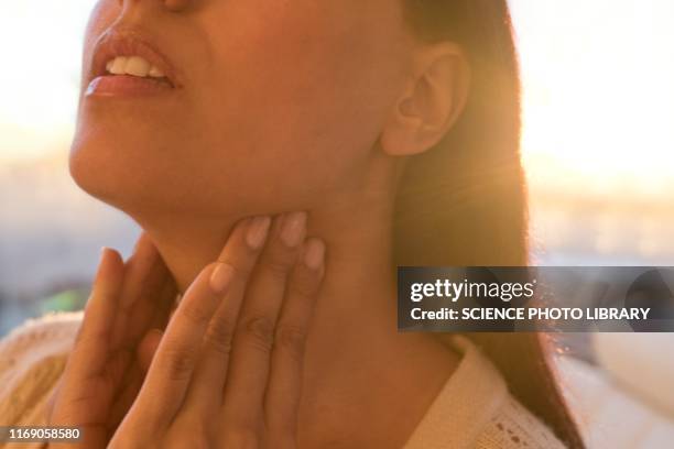 woman touching neck - thyroid gland stock-fotos und bilder