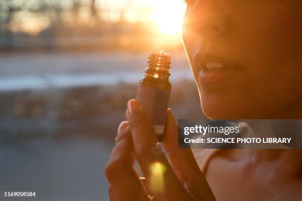 woman holding essential oil bottle - aromatherapy stock pictures, royalty-free photos & images