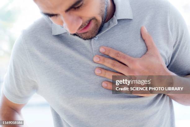 man touching his chest in pain - reflux stock-fotos und bilder