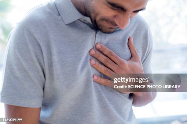 man touching his chest in pain - heartburn stock pictures, royalty-free photos & images