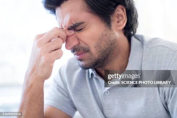 man pinching the bridge of his nose - sinusitis stock pictures, royalty-free photos & images