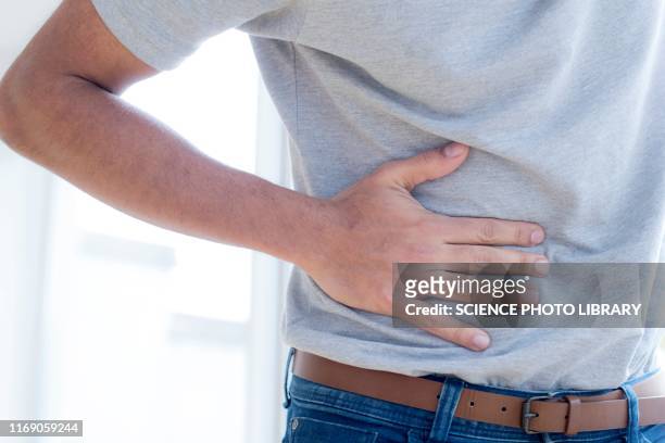 man touching his stomach in pain - appendicitis stock-fotos und bilder