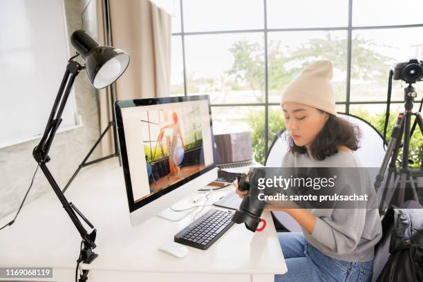 side view of asian female freelancer photographer cheking photos on a digital camera while sitting at the table in workstation - photographer stock-fotos und bilder