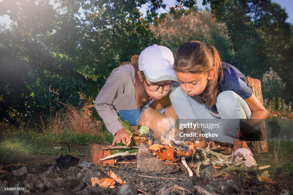 Girls in the forest make a fire.