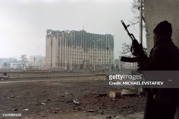 Chechen fighter takes cover from sniper fire in front of the from the presidential palace destroyed by Russian artillery bombardments in Grozny on...