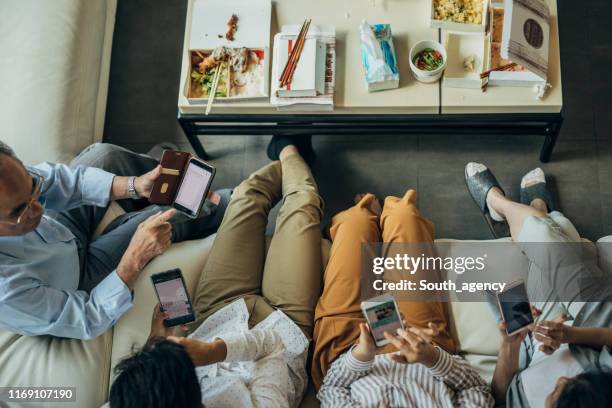 moderne familie zu hause mit smartphones - familie zuhause essen stock-fotos und bilder