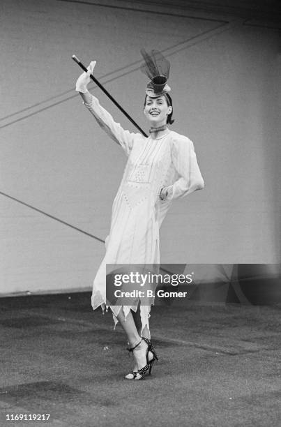 Fashion model wearing outfit by English fashion designer Zandra Rhodes: long sleeve embroidered dress and fascinator, UK, 19th March 1984.