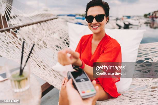 frau im strandcafé mit smartwatch bezahlen - smartwatch pay stock-fotos und bilder