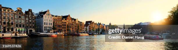 a wide panoramic view of a warm august sunset on amsterdam's amstel canal, where history and dutch culture meet the water - amsterdam canal fotografías e imágenes de stock