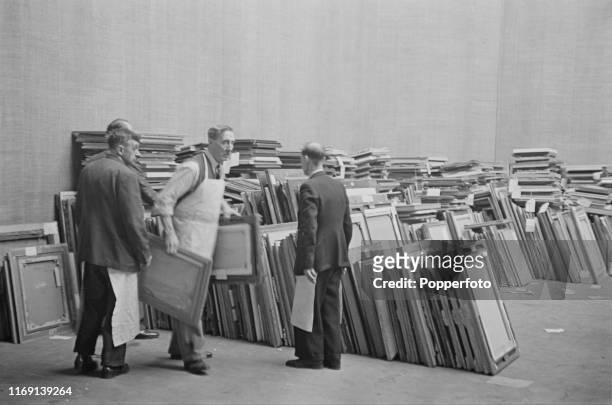 Royal Academy porters carry recently submitted paintings from stacks to be put before the judging committee for possible inclusion in the upcoming...