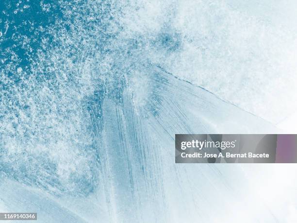 full frame of the textures formed of a block of cracked ice on a soft blue color background. - frost stock photos et images de collection