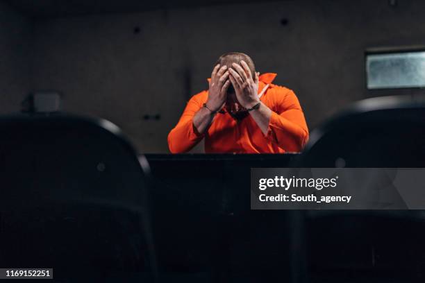 prisionero desesperado sentado solo en la oscura sala de interrogatorios - sentencing fotografías e imágenes de stock