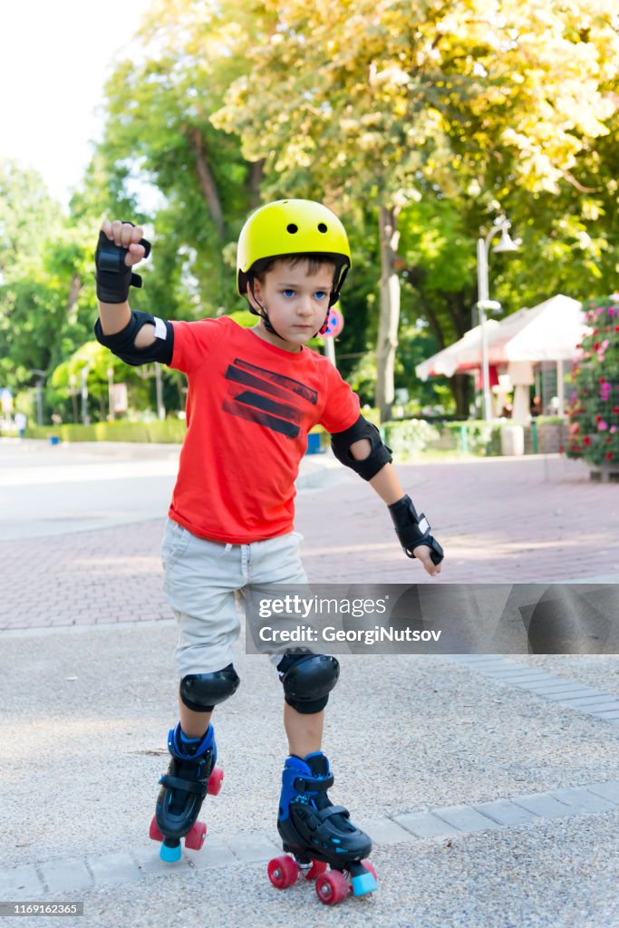 Child with roller skates in a sunny summer park.