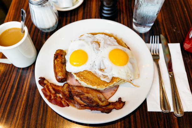 traditional american breakfast with pancakes, fried eggs, bacon, sausage and ham served in a diner - 野菜不足 ストックフォトと画像
