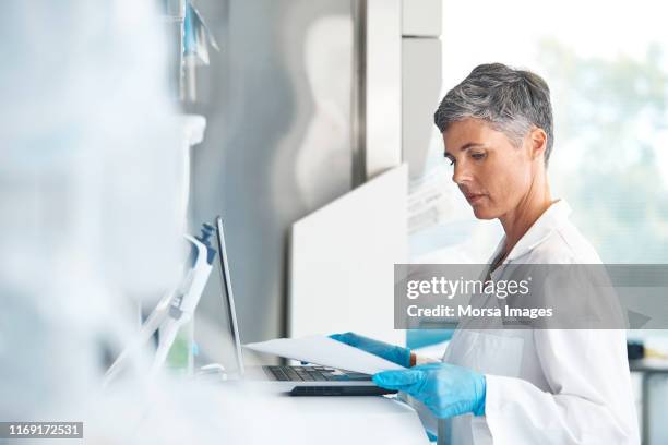 female doctor examining report at research center - medical research paper stock pictures, royalty-free photos & images