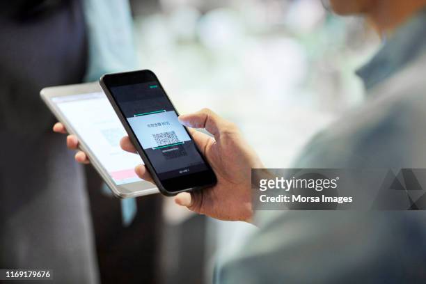 homme payant par le téléphone intelligent dans le café - payer photos et images de collection