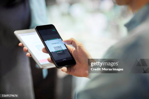 man paying through smart phone in cafe - middle stock pictures, royalty-free photos & images