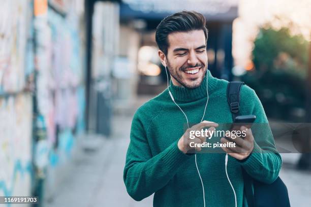 lächelnder mann wählt auf der straße - mann pullover stock-fotos und bilder
