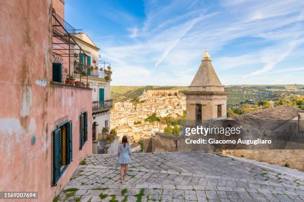 woman climbing the stairs of santa maria delle scale church, ragusa ibla in the background, ragusa, sicily, italy, europe - sicily stockfoto's en -beelden