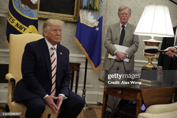 President Donald Trump speaks to members of the media as National Security Adviser John Bolton listens during a meeting with President of Romania...