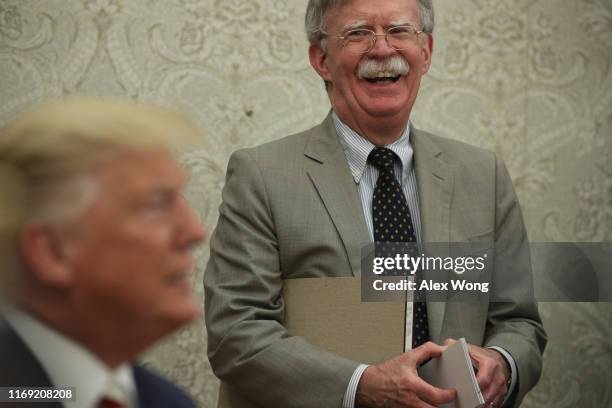 President Donald Trump speaks to members of the media as National Security Adviser John Bolton listens during a meeting with President of Romania...