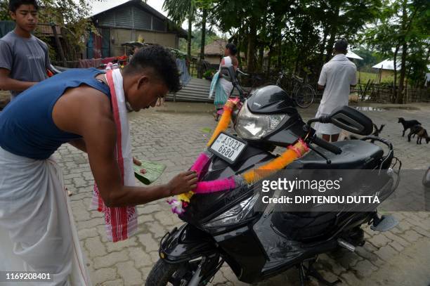 Mishing tribe man performs rituals on his scooter to worship Hindu god of architecture and engineering Biswakarma or Vishvakarman on Majuli island in...
