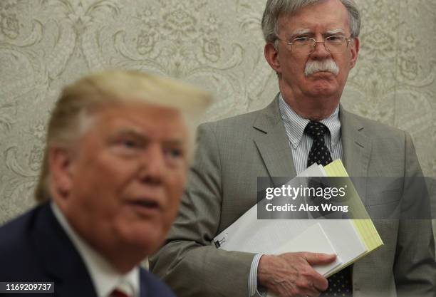 President Donald Trump speaks to members of the media as National Security Adviser John Bolton listens during a meeting with President of Romania...