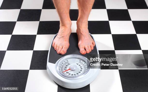 overweight man standing on bathroom scales - weight gain foto e immagini stock