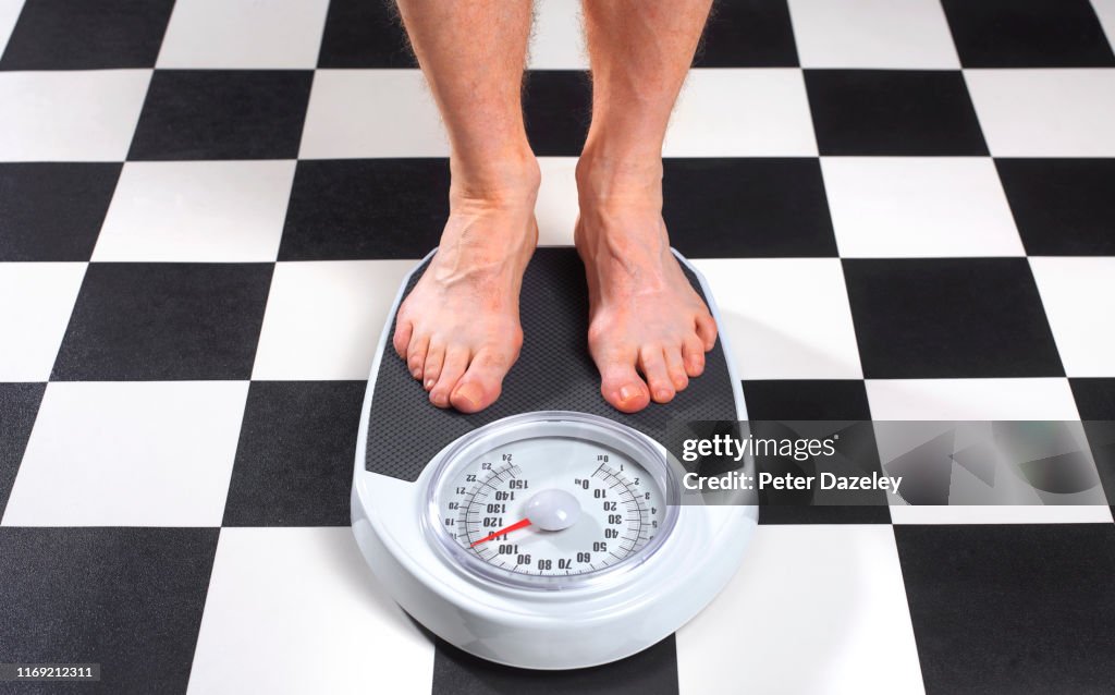 Overweight Man Standing on Bathroom Scales