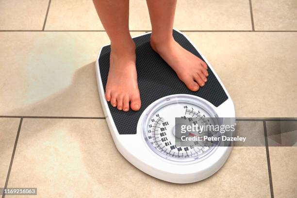 young obese boy on bathroom scales - weegschaal weeginstrument stockfoto's en -beelden
