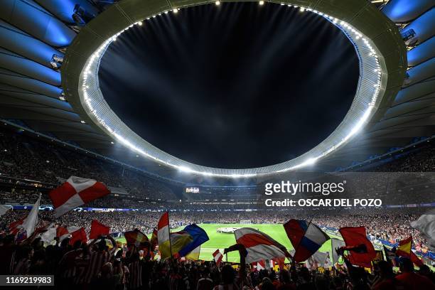 Supporters cheer and wave flags from the stands prior to the UEFA Champions League Group D football match between Atletico Madrid and Juventus, at...