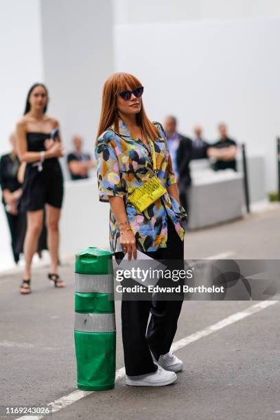 Lily Allen wears sunglasses, a colorful aquarelle flowers print shirt, black pants, a yellow transparent Dior bag, white Nike sneakers, outside Dior,...