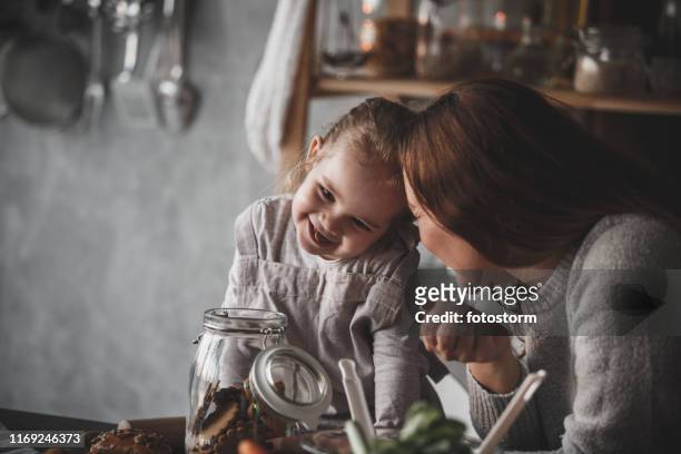 moeder en dochter bonding tijdens het eten van cookies samen - child cookie jar stockfoto's en -beelden