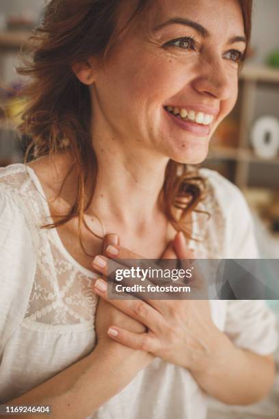 femme excité souriant et retenant des mains sur sa poitrine - main sur la poitrine photos et images de collection